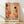 May include: Framed abstract art print leaning against white wall on light wood floor. The poster features warm earth tones with coral, orange, brown and cream organic shapes, black dots, botanical elements, and flowing patterns. Bold black text reads "YAYOI KUSAMA" with Japanese characters below and "OSAKA" in red. Natural wood frame with soft window light creating shadows on textured white wall background.