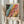 May include: Person holding framed vintage exhibition poster featuring abstract colorful design with flowing patterns in coral, teal, yellow, and black with polka dots and organic shapes. Text shows dates from 1954 and mentions Paris museum. Dried pampas grass visible beside neutral curtains in soft natural lighting.