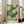 May include: A framed art print featuring Yayoi Kusama's distinctive polka dot style with large circular forms in green and cream tones filled with smaller dots, displayed against a bright living room wall next to a beige armchair. The poster shows "YAYOI KUSAMA" and Japanese characters with "TOKYO" text below the abstract dotted pattern. Natural lighting creates soft shadows on white walls.