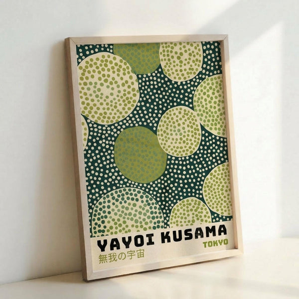 Framed poster with green and cream polka dot pattern featuring overlapping circles in various shades of green against a dark teal background with white dots. The design shows organic circular shapes with different dot textures and patterns within each circle. Text at bottom reads "YAYOI KUSAMA TOKYO" in black and green letters with Japanese characters below. Light wood frame sits propped against white wall.