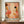 May include: Framed abstract art poster with warm pink, orange, and cream organic shapes, black dots, botanical elements, and Japanese text, displayed on wooden sideboard next to white ceramic vase and stacked books in modern interior with white paneled walls.