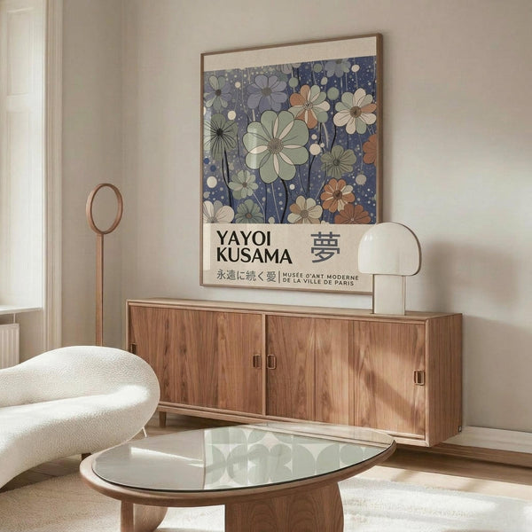 May include: Framed floral art print with blue background and colorful cosmos flowers displayed on wooden sideboard in modern living room. White curved chair and glass coffee table visible. Print features Japanese text and museum attribution. Warm natural lighting creates shadows on light colored walls.