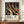 May include: A framed art poster featuring Yayoi Kusama's distinctive polka dot style with colorful circles, tree-like forms, and flowing ribbons against a black background, displayed on a wooden credenza next to a white ceramic vase and stacked books in an elegant room with white paneled walls.