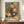 May include: Framed art print displayed on wooden sideboard featuring abstract floral design with radiating daisy-like flowers in orange, green, and cream colors against dark background with scattered dots. Japanese text below reads "Yayoi Kusama" and includes Tokyo reference. White ceramic vase and books sit nearby on warm wood surface against cream wall with white trim molding.