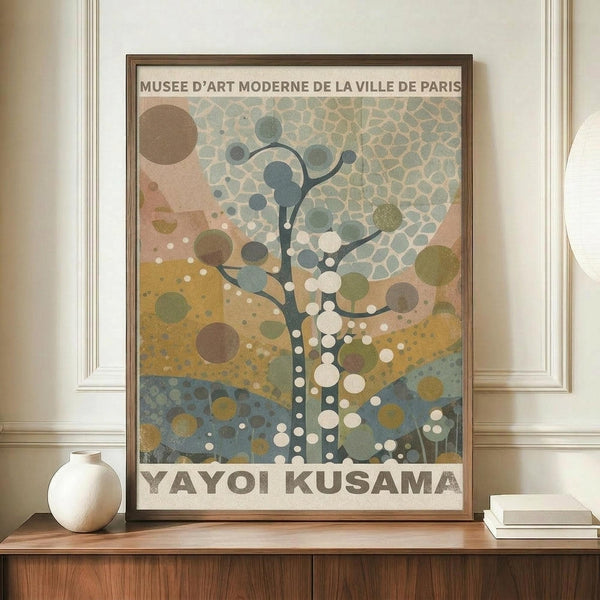 May include: Framed museum poster featuring abstract tree design with circular dots and organic shapes in muted green, yellow, blue and brown tones, displayed on wooden sideboard next to white ceramic vase and books in modern interior with white paneled walls