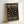 A black poster with colorful polka dots in coral, yellow, sage green, and cream scattered across the surface. White text reads "YAYOI KUSAMA INFINITY DOTS FREVER" at the top and "INFINITY DOTS FOREVER MUSEUM OF CONTEMPORARY ART 22 - APRIL 1986" at the bottom. The print is displayed in a light wood frame leaning against a white wall, showing the poster's full design and minimal modern aesthetic.