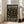 May include: Framed poster with black background and colorful polka dots in orange, yellow, green, and peach tones, displaying white text about a 1986 contemporary art museum exhibition, leaning against white wall next to beige upholstered sofa in bright living room with large windows and natural lighting on light wood floors.