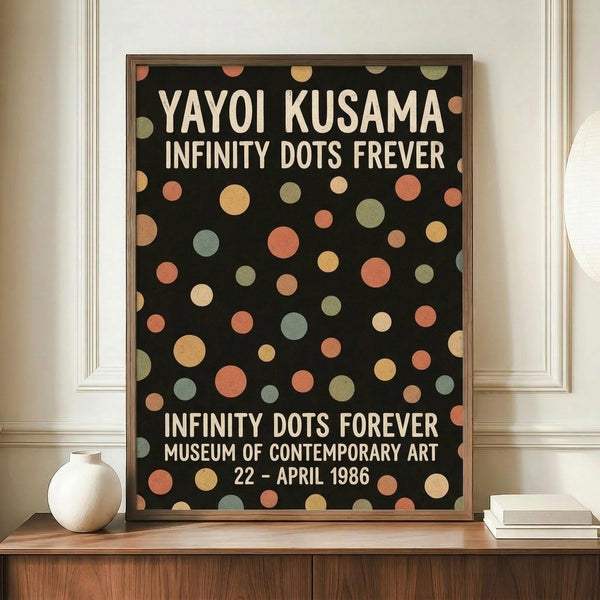 May include: A framed exhibition poster with black background and colorful polka dots in coral, sage green, cream, and gold tones. White text reads "YAYOI KUSAMA INFINITY DOTS FOREVER" and "MUSEUM OF CONTEMPORARY ART 22 - APRIL 1986". The poster is displayed on a wooden credenza alongside a white ceramic vase and stacked books in a minimalist room with cream walls and white trim.