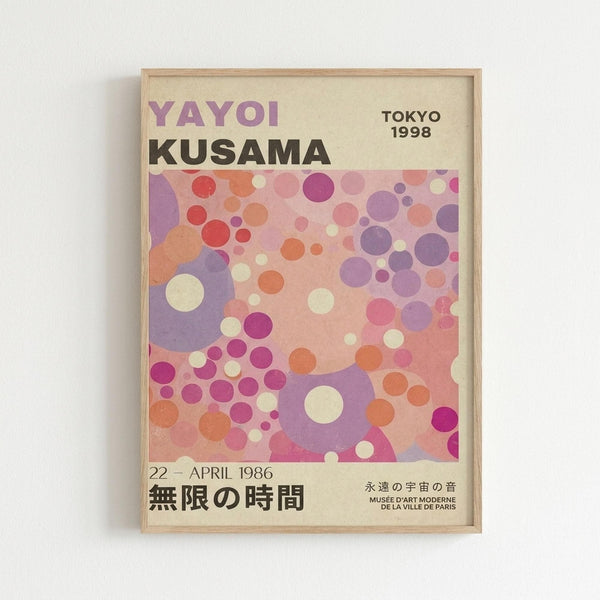 A framed exhibition poster featuring abstract artwork with overlapping circles in purple, pink, coral, and cream colors. The poster displays "YAYOI KUSAMA" in large text at the top, "TOKYO 1998" in the upper right, and Japanese text at the bottom along with "22 - APRIL 1986" and "MUSEE D'ART MODERNE DE LA VILLE DE PARIS". The artwork shows Kusama's signature polka dot style with various sized circles creating a dreamy, layered composition in soft pastel tones.