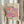 May include: Person holding framed art poster featuring colorful polka dot pattern in pink, purple, orange and cream tones. Text reads "Yayoi Kusama Tokyo 1998" and Japanese characters. Light wooden frame against neutral curtained background with dried pampas grass visible on left side. Person wearing beige ruffled sleeve top.