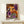 May include: Framed art print leaning against white wall on light wooden console table with small white gift box. Artwork features vibrant abstract design with orange, purple, black and white circular patterns and dots in contemporary style. Japanese text visible at bottom. Natural lighting creates soft shadows on minimalist interior setting.