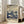 May include: Framed art print featuring stylized mushrooms and plants in navy blue and cream tones with flowing sky pattern and scattered dots, displayed on wooden floor beside beige sofa in bright living room with large windows