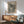 May include: Framed vintage museum poster featuring black polka dot pattern on cream background, displayed above wooden sideboard with white ceramic lamp in modern living room setting with mint green upholstered armchair and natural sunlight streaming across white walls.