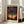 May include: Framed poster leaning against white wall next to beige sofa in bright living room. Artwork features colorful dotted tree with vibrant polka dot canopy in blues, oranges, and purples against cosmic background. Text reads "YAYOI KUSAMA" at top and "TOKYO 1998" at bottom with Japanese characters. Light wood frame on hardwood floor near large windows.