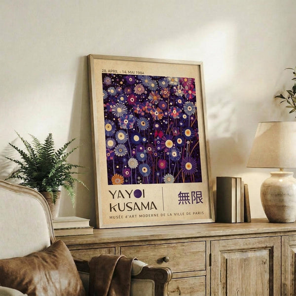 May include: Framed poster with purple background featuring colorful abstract flowers and circles in pink, orange, and yellow tones, displayed on rustic wooden sideboard next to fern plant, ceramic vase, and books in neutral-toned living room setting with beige chair visible.