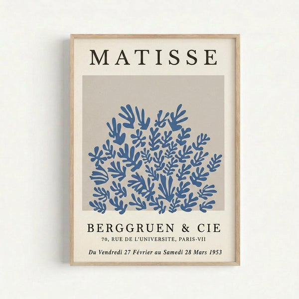 May include: Framed reproduction of a Matisse exhibition poster featuring blue coral-like cutout shapes on a beige background. Light wood frame hangs on white wall. Black text reads "MATISSE" at top and "BERGGRUEN & CIE" with Paris gallery details and 1953 dates below the organic blue botanical forms.