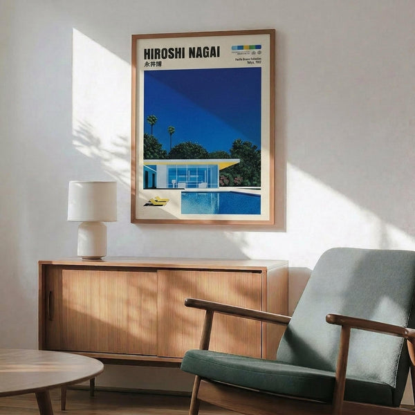 May include: Framed poster showing modern white house with swimming pool under bright blue sky with palm trees, displayed above wooden sideboard with white ceramic lamp in mid-century modern living room with sage green upholstered chair and round coffee table