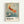 May include: Framed vintage exhibition poster featuring a golden-orange koi fish swimming among cherry blossoms in traditional Japanese art style. The fish displays detailed scales and flowing fins against a soft blue-green watercolor background with delicate white flowers and willow branches. Black text below reads "OHARA SHOSON" with Japanese characters and museum exhibition details from 1972. Natural wood frame hangs on white wall.
