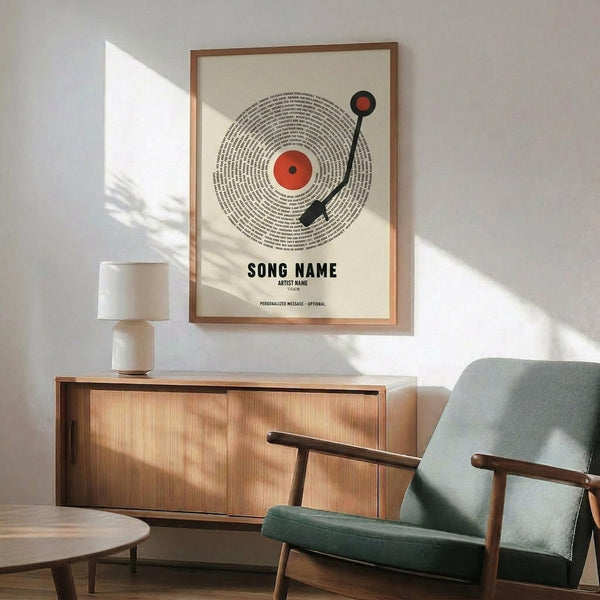 May include: Framed poster print featuring a vinyl record design with red center label and black tonearm, displayed above a mid-century modern wood credenza with table lamp. Green upholstered chair with wooden arms sits nearby in minimalist living room with white walls and natural lighting.
