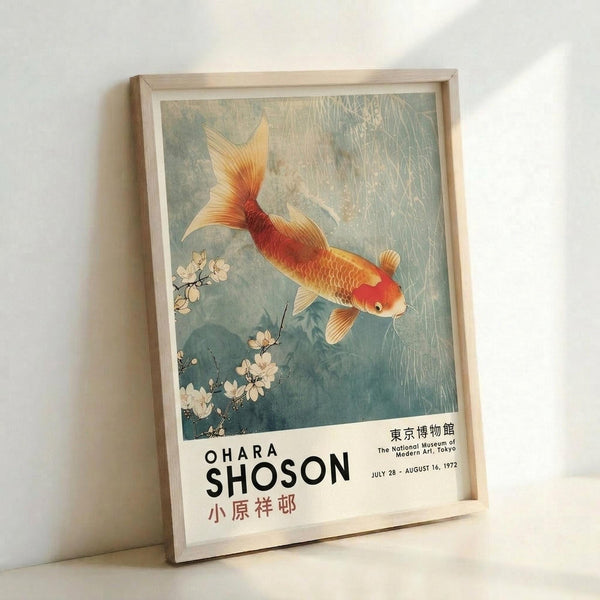 May include: Framed vintage-style exhibition poster leaning against white wall, featuring Japanese artwork of golden-orange koi fish swimming among white cherry blossoms in blue-green water with rain-like streaks. Light wooden frame with white matting. Text shows "OHARA SHOSON" with Japanese characters and museum exhibition details from 1972. Soft natural lighting creates gentle shadows on wall.