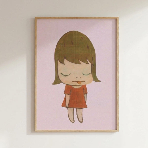 May include: Framed art print showing a cartoon-style illustration of a young girl with brown bob haircut, closed eyes, and tongue sticking out, wearing an orange-red dress. The character is drawn in a simple, minimalist style against a soft pink background. The artwork is displayed in a light wooden frame hanging on a white wall.