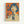 Vintage-style Japanese advertisement poster featuring a woman with short dark hair and bangs holding a glass Coca-Cola bottle. The artwork uses a retro color palette of orange, blue, and cream with Japanese text characters prominently displayed. The illustration has a mid-century modern aesthetic with halftone dot shading effects. The poster is displayed in a thin wooden frame against a white wall.