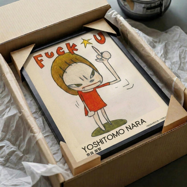 May include: Framed poster print featuring cartoon-style illustration of a blonde child character in red clothing making an obscene gesture, with colorful text above and artist signature below. Black frame sits in open cardboard shipping box with protective wrapping materials on white surface.