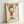 May include: Framed art print leaning against white wall showing cartoon-style character with blonde bob haircut, red dress, and raised middle finger. Bold red lettering spells profanity at top with yellow star. Artist name "YOSHITOMO NARA" printed at bottom with Japanese characters and date. Light wooden frame surrounds white paper with colored pencil or marker-style illustration.