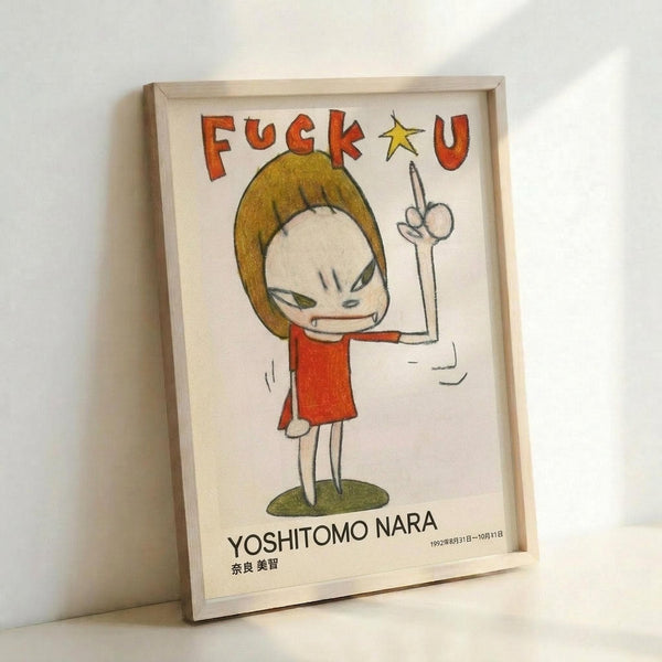 May include: Framed art print leaning against white wall showing cartoon-style character with blonde bob haircut, red dress, and raised middle finger. Bold red lettering spells profanity at top with yellow star. Artist name "YOSHITOMO NARA" printed at bottom with Japanese characters and date. Light wooden frame surrounds white paper with colored pencil or marker-style illustration.