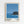 May include: Framed art print hanging on white wall showing coastal scene with dark rocky outcrop and vegetation against blue ocean and sky, featuring bold graphic style in blues and teals with white matting and light wood frame