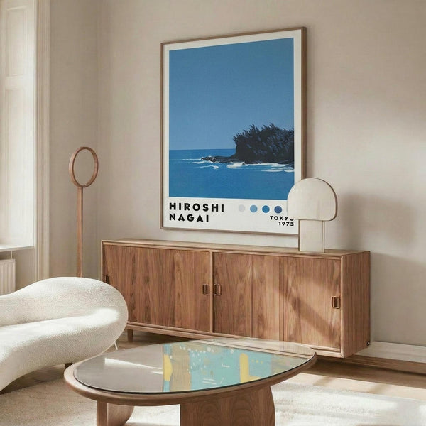 May include: Framed poster featuring blue ocean scene with small forested island, displayed above mid-century modern walnut credenza in minimalist living room with cream chair, glass coffee table, and brass floor lamp