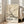May include: Framed vintage Japanese art poster featuring white bird perched on flowering cherry blossom branches against cream background, displayed on light wood floors next to beige upholstered sofa in bright room with white walls and large windows casting natural light shadows.