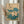 May include: Framed vintage Japanese botanical print featuring two blooming lotus flowers with cream-colored petals and green centers, surrounded by large teal and sage green lotus leaves. The artwork displays traditional Asian calligraphy and red seal stamp on aged beige paper. Light wooden frame hangs on white wall beside dried pampas grass stems, with soft natural lighting creating gentle shadows.