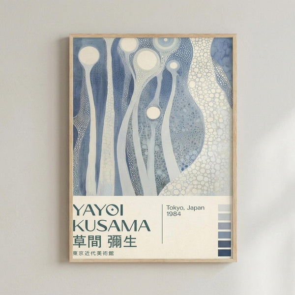 May include: Framed poster with abstract flowing forms in blue and cream tones, featuring organic curved shapes and dotted patterns reminiscent of underwater or cellular structures. The artwork displays Japanese text below the artist name, with exhibition details showing Tokyo, Japan 1984. Light wood frame hangs on white wall, with small color palette squares visible in bottom right corner.