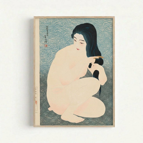 Vintage Japanese woodblock print showing a nude woman with long black hair combing her hair, seated against a blue-green textured background. The artwork features soft peachy skin tones and includes traditional Japanese calligraphy and red seal stamps. Displayed in a light wooden frame against a white wall.