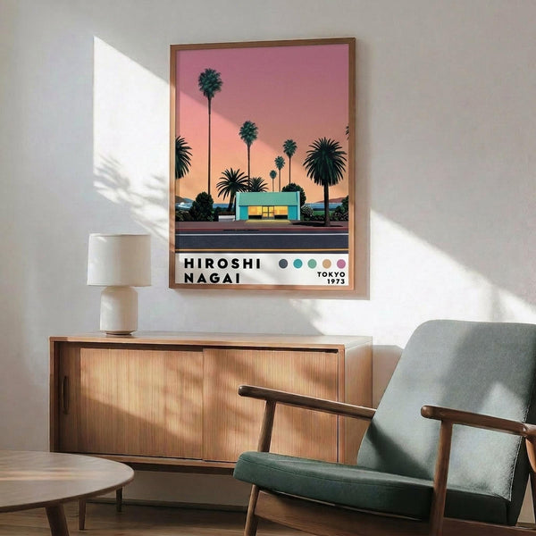 May include: Framed poster print on white wall above wood sideboard, featuring palm trees against pink sunset sky with modernist building. Mid-century modern living room with sage green upholstered chair, round coffee table, and ceramic table lamp. Warm natural lighting creates geometric shadows on wall.