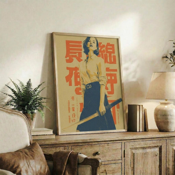 May include: Framed vintage-style poster featuring a woman in yellow shirt and blue skirt holding a katana sword, with red Japanese text on cream background. Displayed on rustic wooden sideboard alongside books, ceramic vase, and fern plant in neutral-toned living room setting.