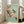 May include: Large framed vintage Japanese woodblock print featuring pink cherry blossoms and a teal bird perched on flowering branches against sage green background, displayed on light wooden floors next to beige upholstered chair in bright sunlit room with white walls and windows.