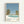 May include: Framed poster print hanging on white wall showing tropical poolside scene with turquoise swimming pool, palm trees, blue sky, and small island in distance. Light wood frame surrounds artwork featuring muted blue, green, coral and cream color palette. Text reads "HIROSHI NAGAI" and "TOKYO 1973" with colored dots accent. Clean minimalist styling in contemporary interior setting.
