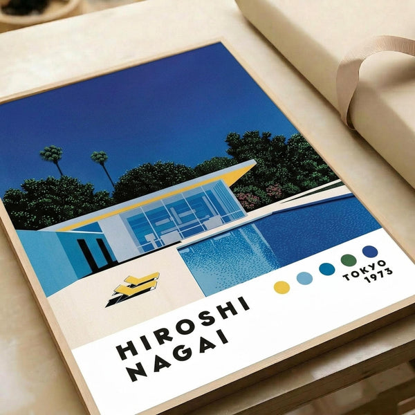 May include: Modern art print featuring a mid-century pool house with large glass windows, blue swimming pool, and palm trees against a bright blue sky. The minimalist illustration uses bold colors - blues, yellows, and whites - in a retro Japanese pop art style. Print sits on white paper against cream fabric background with soft lighting creating gentle shadows.