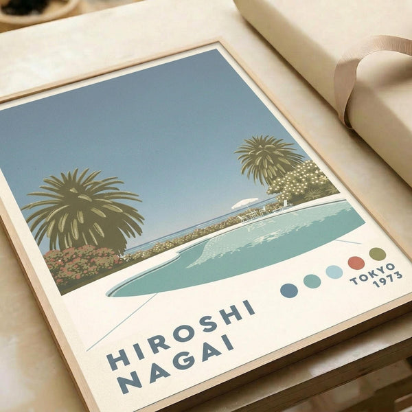 Vintage-style travel poster featuring a tropical beach scene with two palm trees, turquoise water, and white sandy shore under a pale blue sky. Text reads "HIROSHI NAGAI" and "TOKYO 1973" with colorful dots. The print has a cream border and is shown in a light wooden frame on white paper wrapping with beige ribbon.