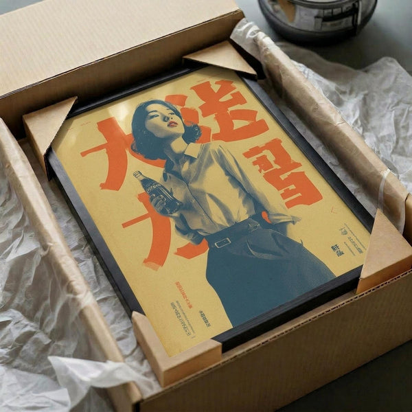 May include: Framed vintage-style Coca-Cola poster featuring a woman in 1940s attire holding a Coke bottle against yellow background with red Japanese text, displayed in black frame inside cardboard shipping box with protective wrapping materials on white surface