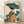 May include: Framed Japanese woodblock print artwork displayed on wooden floor against white wall. Features woman in traditional kimono with floral patterns in teal, coral and cream colors, holding blue paper umbrella. Surrounded by large teal lotus leaves. Art style shows classic ukiyo-e technique with delicate linework and muted color palette on cream background. Natural wood frame complements the organic tones of the vintage-inspired Asian art.