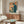 May include: Retro Japanese computer poster with orange text and figure using vintage desktop computer, displayed above wooden credenza with sliding doors in modern living room setting with white curved chair, glass coffee table, and contemporary lighting