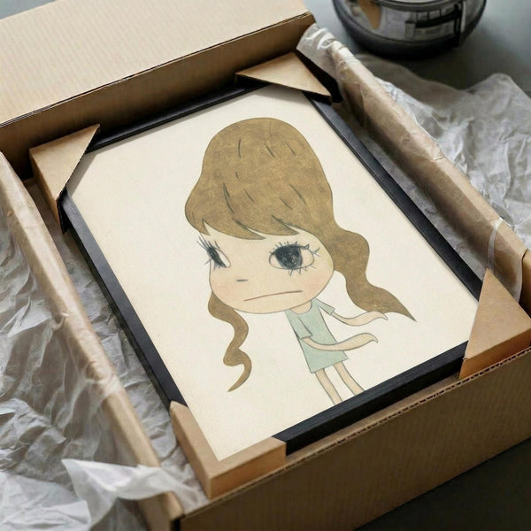 May include: Framed art print of a cartoon-style girl with long brown wavy hair and large eyes, wearing a light green dress, displayed in a black frame inside an open cardboard shipping box with protective wrapping materials and wooden frame corners visible around the package.