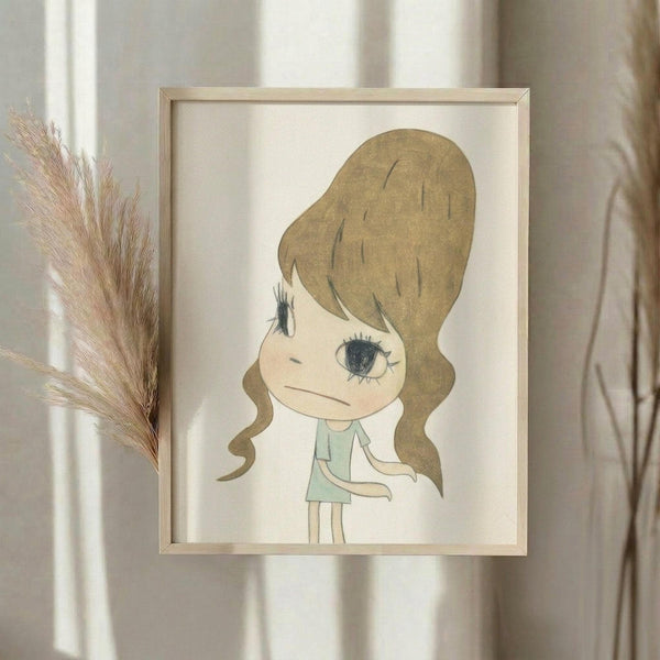 May include: Framed artwork displayed on white wall showing a cartoon-style illustration of a young girl with large brown beehive hairdo, oversized blue eye, and mint green dress. The drawing has a melancholic expression rendered in soft earth tones on cream background. Natural wood frame surrounds the piece, with dried pampas grass visible to the left and soft natural lighting creating gentle shadows.