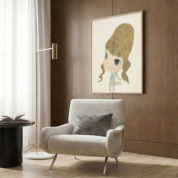 May include: Framed art print featuring a cartoon-style girl with voluminous blonde beehive hair and large eyes, wearing a light green dress, displayed on wood-paneled wall above a cream upholstered armchair with geometric patterned pillow, beside a brass floor lamp and dark round side table with open book