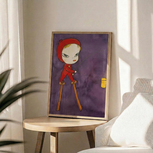 May include: Framed artwork displaying a stylized character in red hooded outfit standing on stilts against purple background, positioned on round wooden side table next to beige upholstered chair with white throw pillow, green plant leaves visible in corner, natural sunlight streaming across white walls creating soft shadows in modern living room setting.