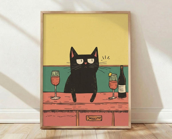 May include: Framed poster print leaning against white wall on light wood floor. Artwork shows black cat with half-closed eyes sitting on coral-pink counter between two wine glasses filled with red wine and dark bottle. Cat has pink inner ears and whiskers with small motion lines. Background features yellow upper wall and teal lower section. Simple illustration style with bold colors in natural wood frame.