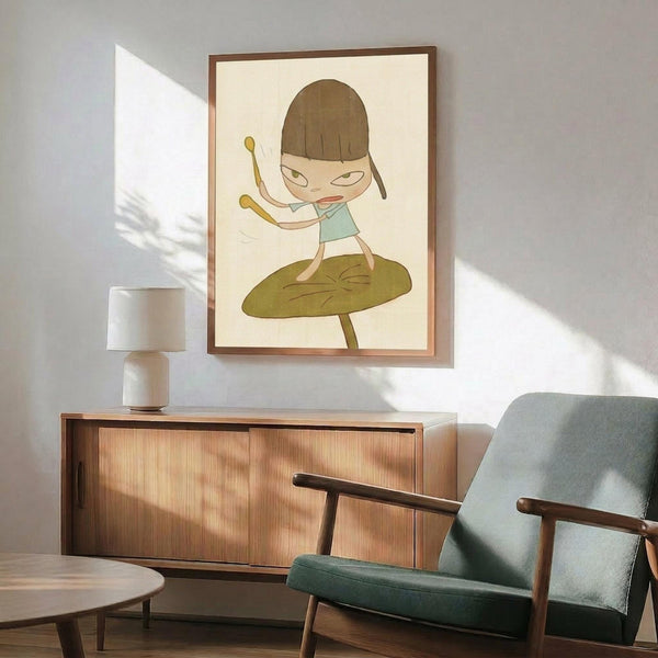 May include: Framed artwork showing a cartoon-style girl with brown bob haircut and bangs, wearing light blue top, standing on large green leaf while holding drumsticks in dynamic pose. Art has cream background with thin brown frame, displayed above wooden sideboard with white ceramic lamp. Teal upholstered armchair with wooden frame visible in foreground of modern mid-century styled room with white walls and natural sunlight casting shadows.